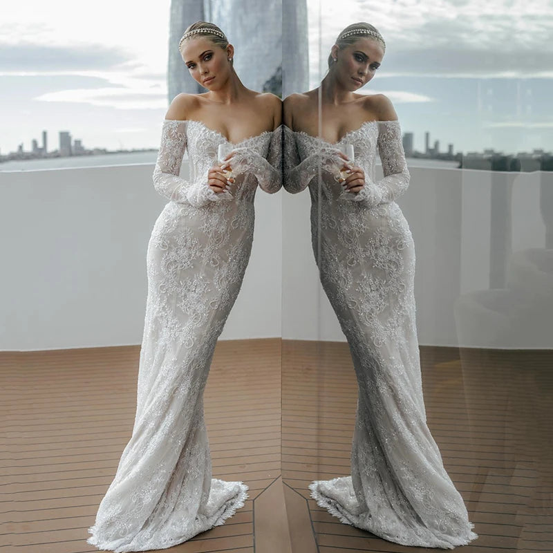Off-shoulder lace mermaid wedding dress with beaded details and full-length illusion sleeves for romantic elegance.