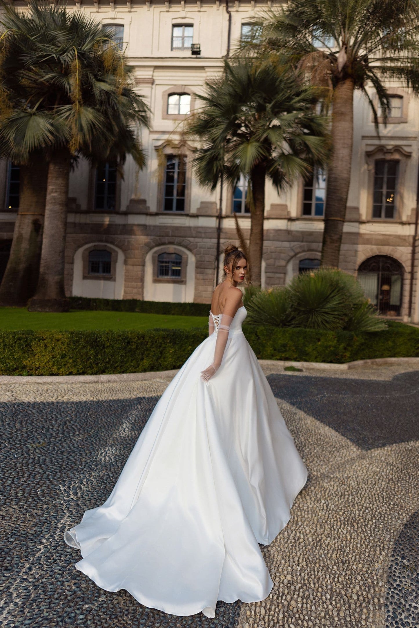 Elegant bridal gown with voluminous satin skirt, long train, and eye-catching floral detailing on sleeves, ideal for luxury weddings.