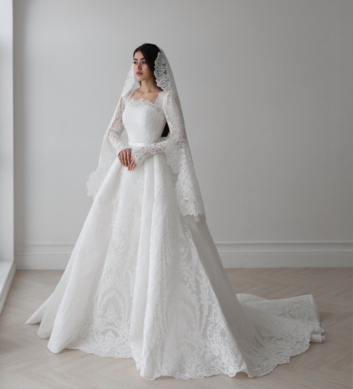 Scalloped lace detailing on sleeves and hemline of elegant ball gown wedding dress