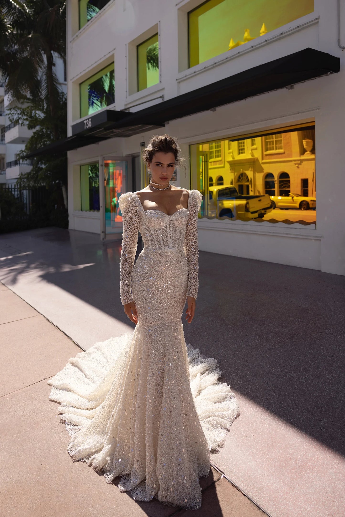 Front view of structured corset bridal gown with full-body embellishment and dramatic train.
