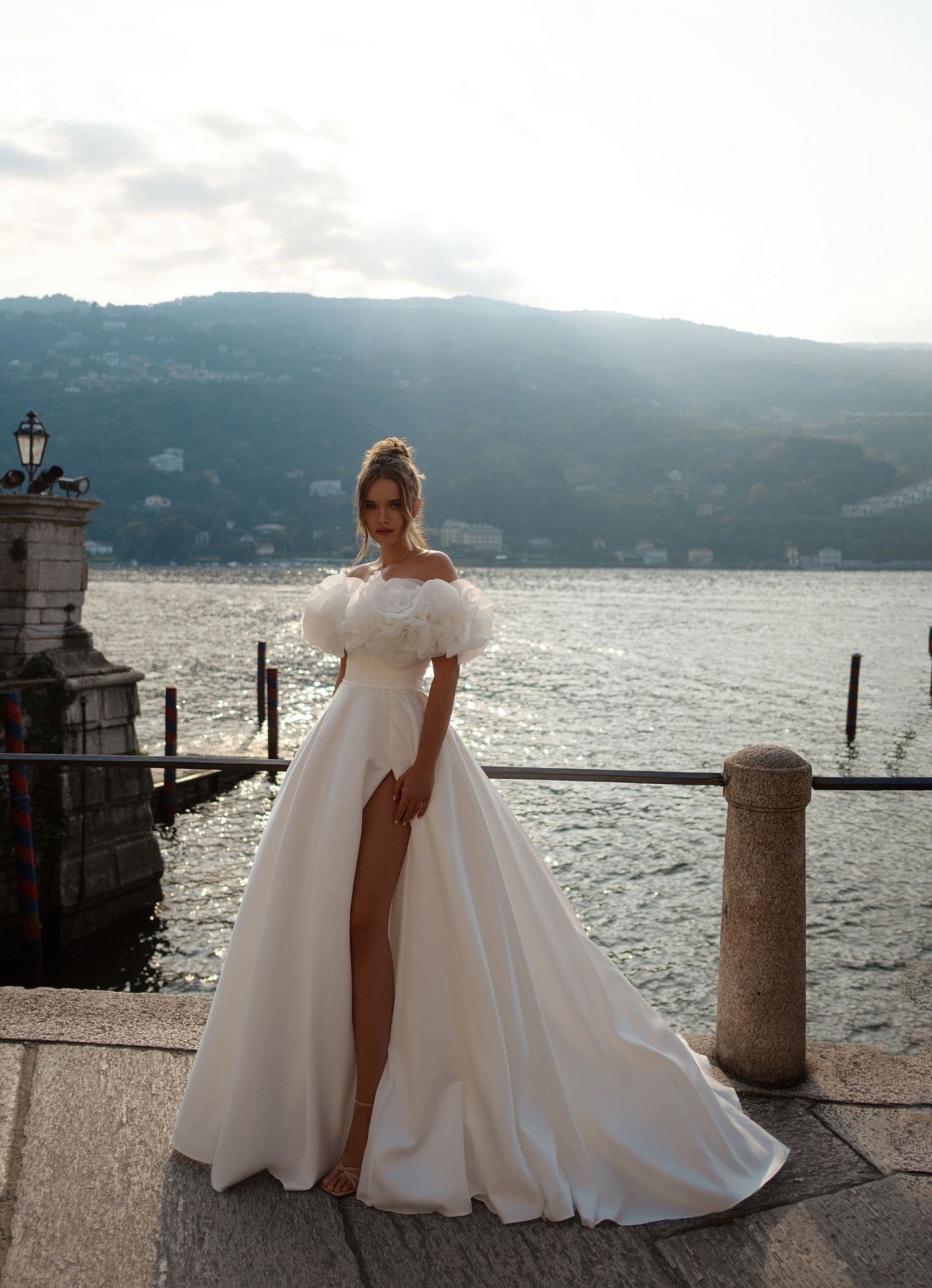 Modern princess-style wedding gown featuring an off-shoulder neckline, leg-revealing high slit, and couture-level floral sleeve accents.