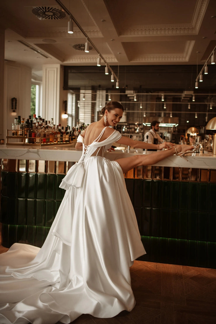 Back view of wedding gown with lace-up detail, oversized bow, and cathedral-length train.