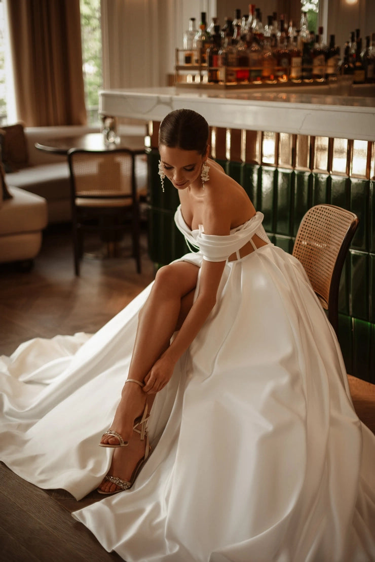Bride adjusting heels while wearing a custom crystal corset wedding dress with side slit.