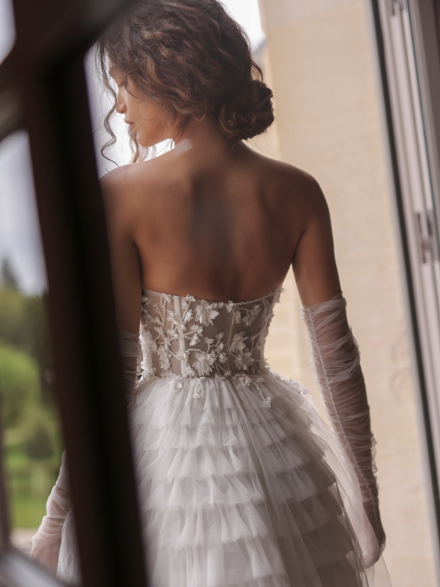 Back view of strapless lace wedding gown with soft ruffle layers