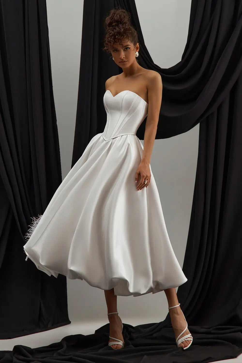 Side view of satin midi bridal gown featuring a flattering bubble hem and tailored fit