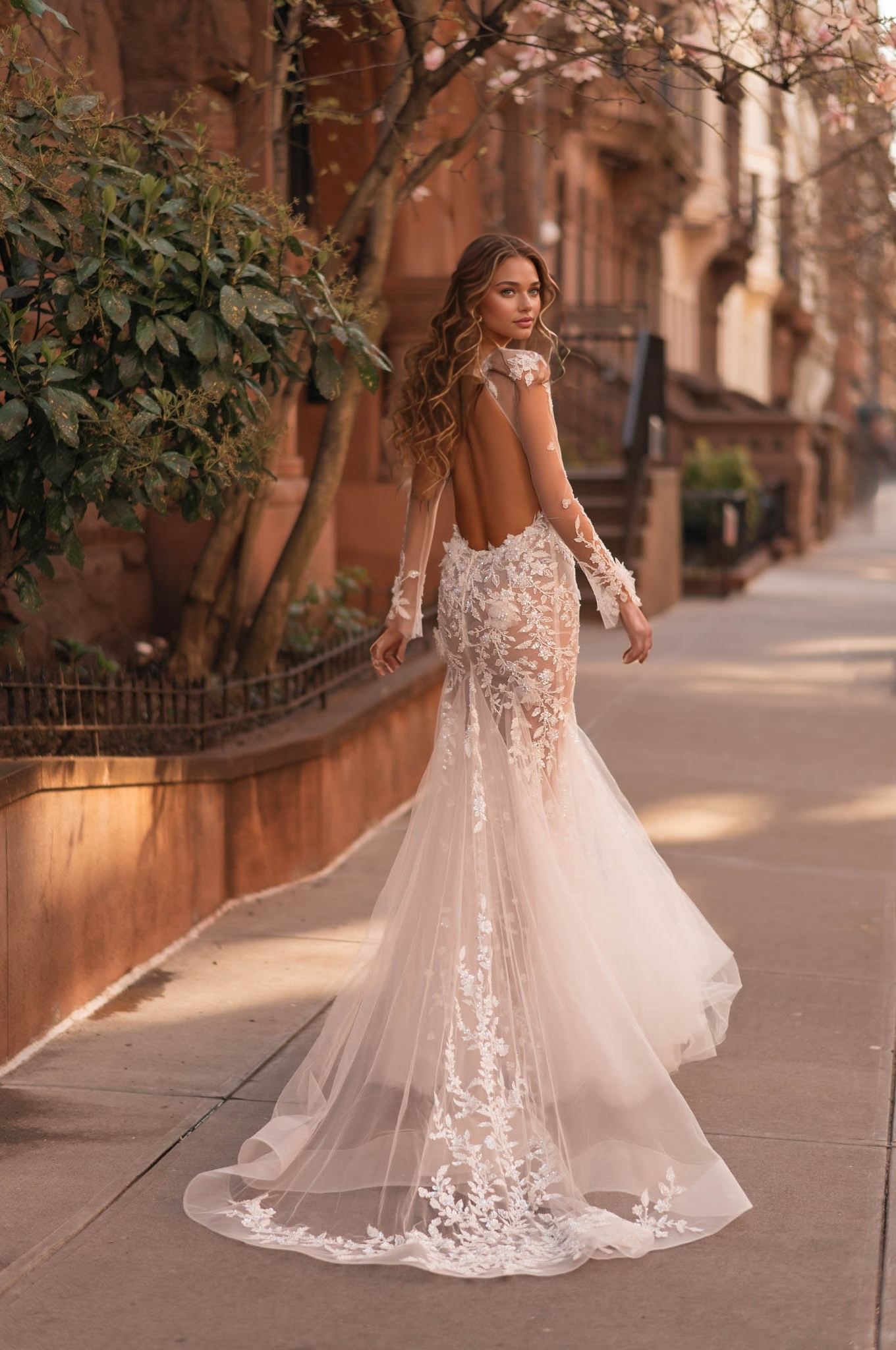 sheer illusion long-sleeve lace wedding dress with floral appliqués and long train near cherry blossoms