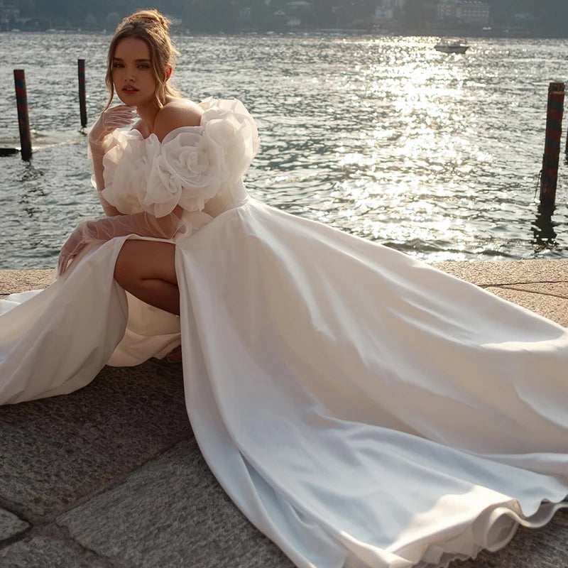 White bridal gown featuring high slit, sculpted bodice, and statement floral puff sleeves, ideal for beach or outdoor wedding ceremonies.