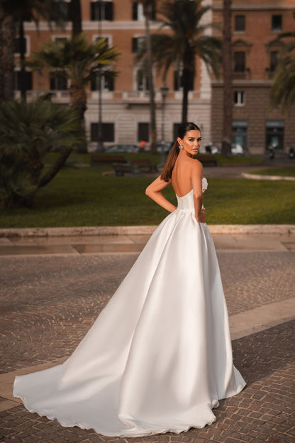 Trendy Modern Off-White Satin Bridal Gown With Sweetheart Neckline, Waist Bow, Sleeveless Design, And Light Flared Train With High Slit