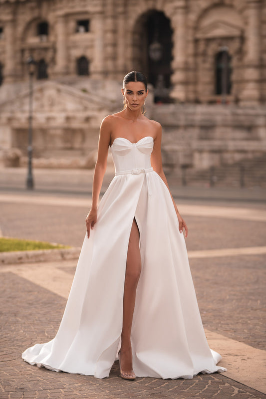 Trendy Modern Off-White Satin Bridal Gown With Sweetheart Neckline, Waist Bow, Sleeveless Design, And Light Flared Train With High Slit