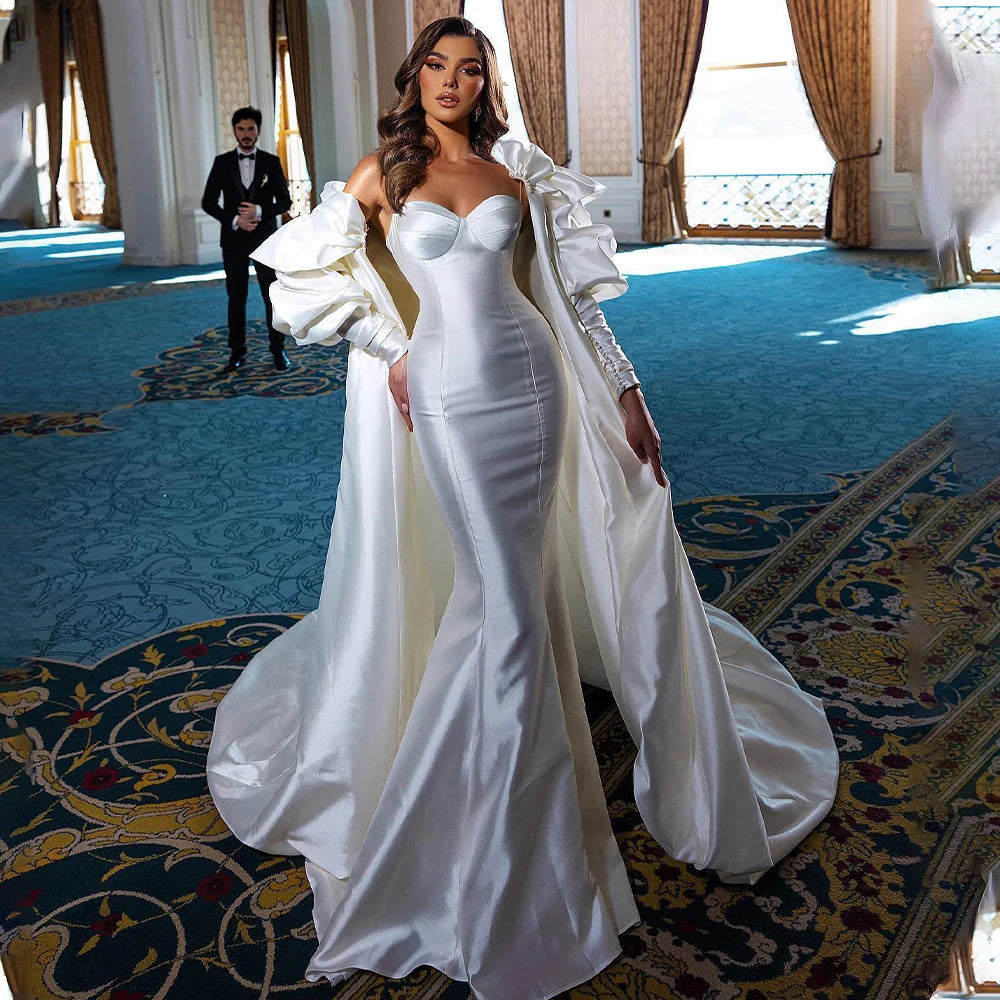 Satin mermaid wedding dress with spaghetti straps and detachable puff sleeve cape with dramatic train.