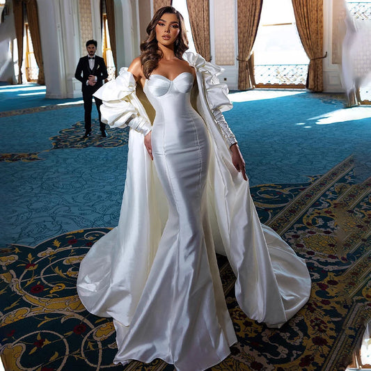 Satin mermaid wedding dress with spaghetti straps and detachable puff sleeve cape with dramatic train.