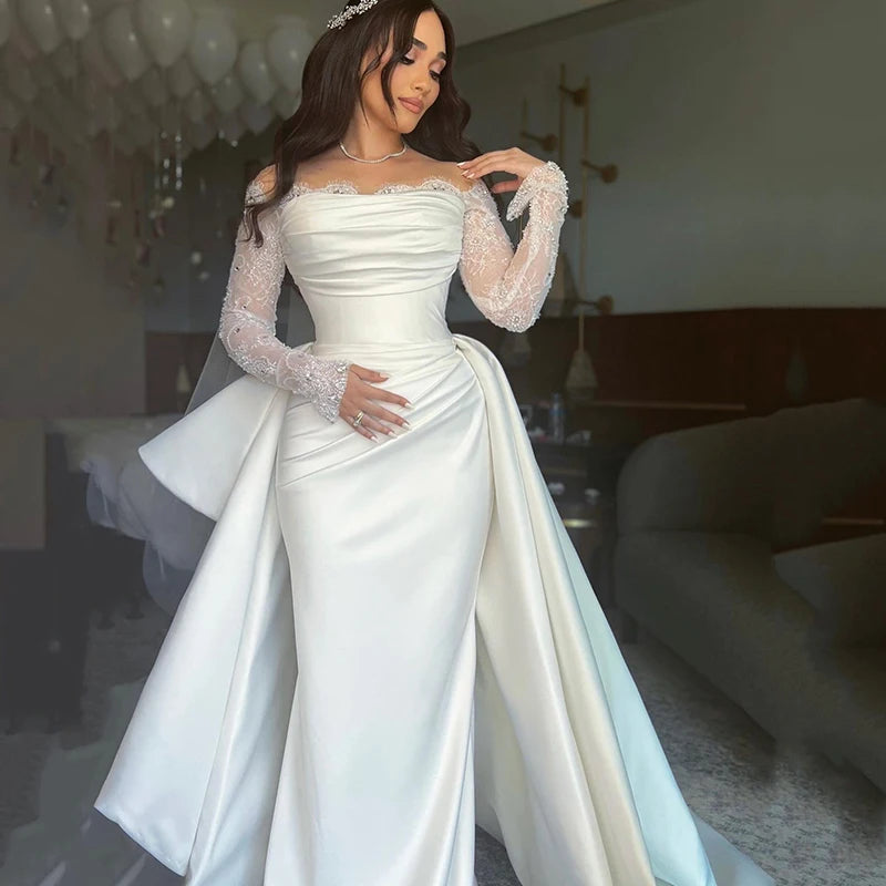 Off-shoulder mermaid wedding dress with long lace sleeves, fitted satin skirt and romantic neckline.

