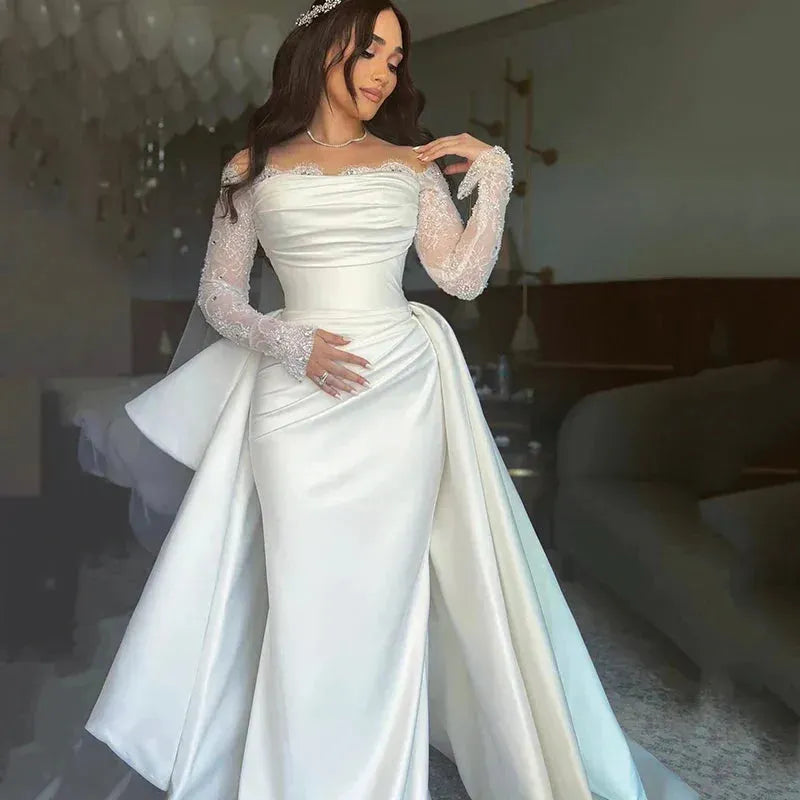 Bridal gown with satin mermaid silhouette, ruched waist detail, and beaded lace sleeves.

