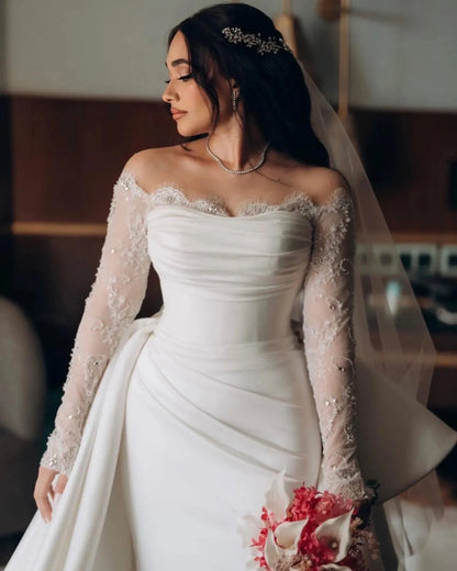 White mermaid bridal dress featuring beaded lace, off-shoulder bodice and custom fit silhouette.

