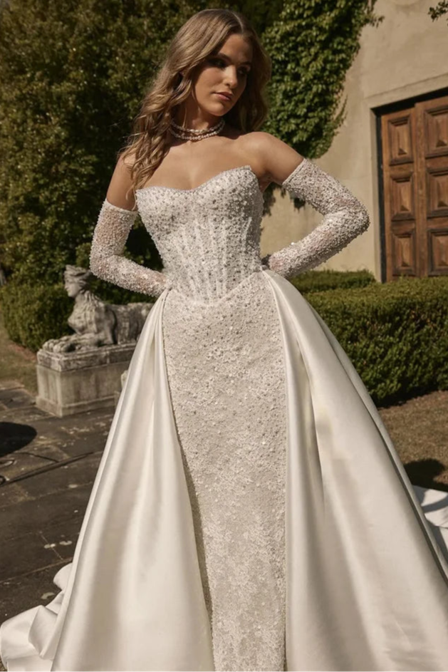 Bridal gown with detachable satin overskirt for a dramatic princess-style look, ideal for a castle wedding theme.