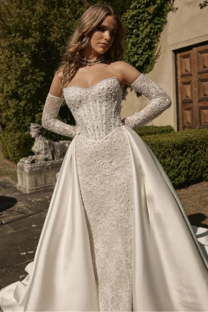 Bridal gown with detachable satin overskirt for a dramatic princess-style look, ideal for a castle wedding theme.