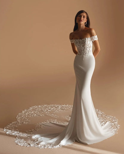 Romantic off-shoulder bridal gown with floral lace appliqué on bodice and hemline.