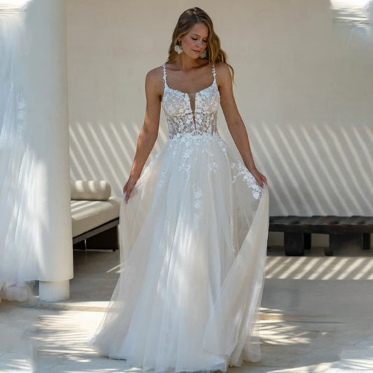 Romantic A-line wedding dress with floral lace appliqués, sheer bodice, and thin spaghetti straps for a light, airy bridal look.