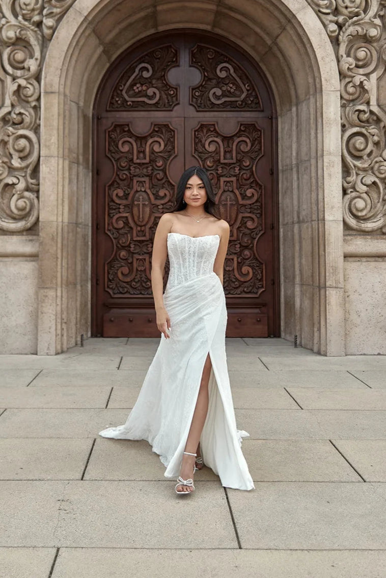 Modern mermaid bridal gown in allover lace, featuring sultry side slit and sweeping train
