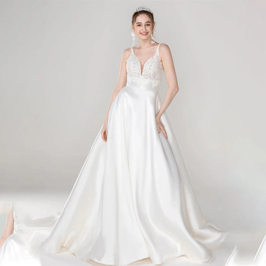 Luxurious satin A-line wedding dress with V-neckline, lace straps, and flowing skirt for timeless bridal elegance.