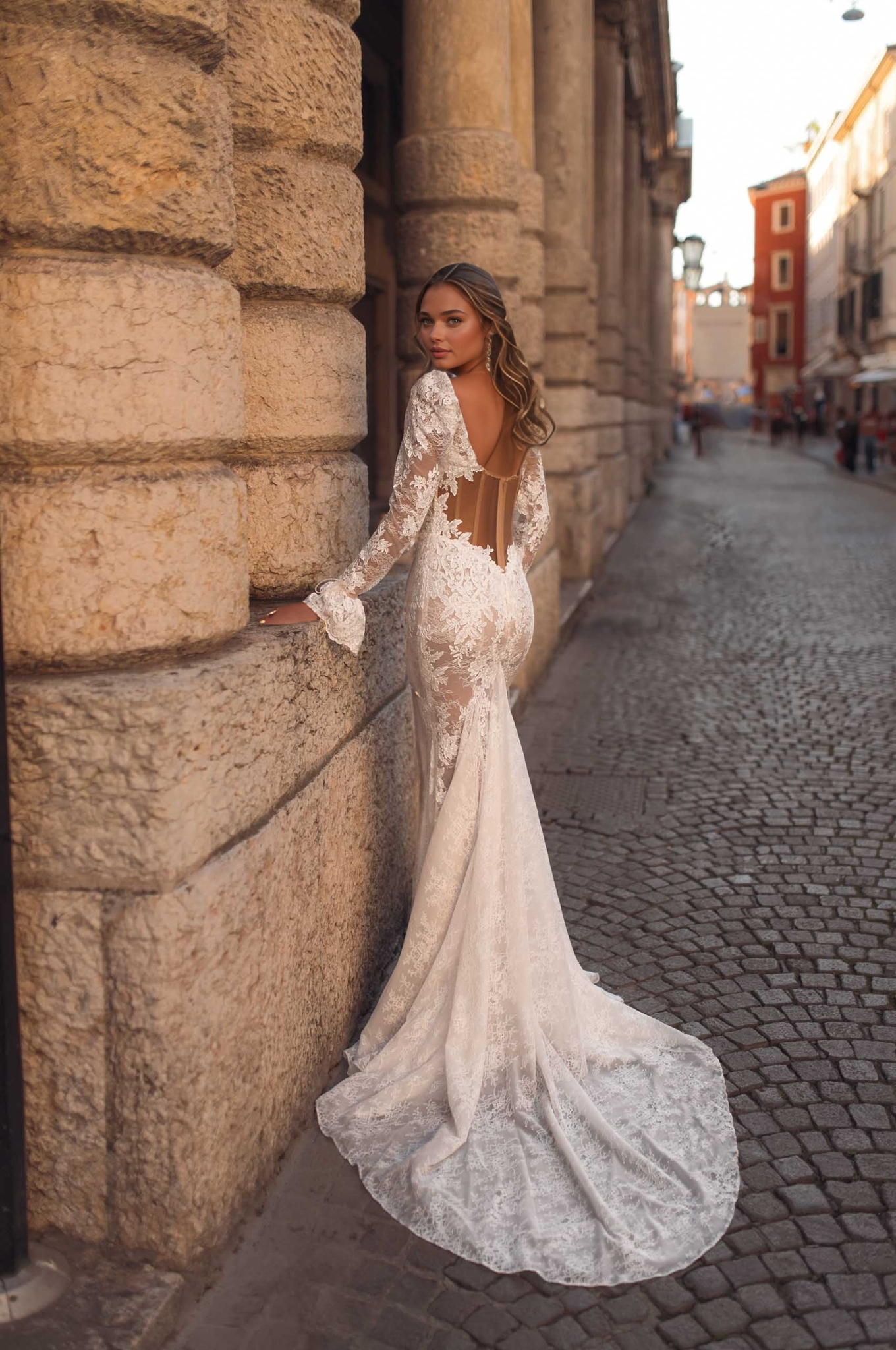 woman wearing a floral appliqué square-neck long-sleeve sheer illusion wedding dress in an outdoor venue