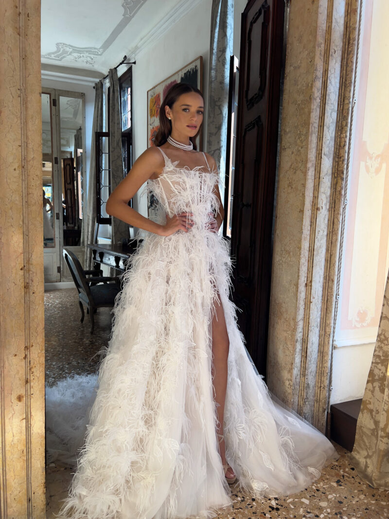 Feather embellished tulle wedding dress back view showcasing chapel train